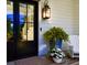Stylish front door with sidelights, complemented by a cozy porch setup with rocking chair and plants at 31 Seagrass Ln, Isle of Palms, SC 29451