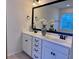 A dual vanity with white cabinets, dark hardware, marble countertop, and a large framed mirror creates a luxurious bathroom space at 317 Whispering Breeze Ln, Summerville, SC 29486