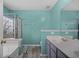 Bathroom featuring a double sink vanity, framed mirror, and glass shower with a tub, all with a teal accent wall at 406 Brookfield Ln, Goose Creek, SC 29445
