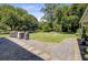 Large, level backyard with well-maintained lawn, mature trees, and patio surrounded by gravel at 422 Geddes Ave, Charleston, SC 29407