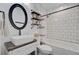 Well-lit bathroom featuring a vessel sink, black hardware, subway tiled shower-tub, and wall shelving at 422 Geddes Ave, Charleston, SC 29407