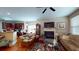 Cozy living room with a fireplace, TV, ceiling fan, and hardwood floors, seamlessly connecting to the kitchen at 4969 Franconia Dr, Summerville, SC 29485
