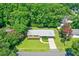 An aerial view of a quaint brick home with a well-manicured lawn and lush trees surrounding the property at 7 Plainfield Dr, Charleston, SC 29407