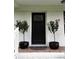 Covered front porch featuring black front door, potted plants, and a decorative welcome mat at 702 N N Palmetto St, Summerville, SC 29483