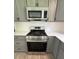 Modern stainless steel gas range and microwave with sleek gray cabinets and hardware at 702 N N Palmetto St, Summerville, SC 29483