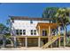 A new beach house exhibits a spacious elevated deck and stairs, with lush vegetation and a clear blue sky backdrop at 817 Cheehaw St, Edisto Island, SC 29438