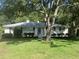 Charming, single-story home with a white brick exterior, a gray roof, and surrounded by lush greenery at 874 Evans Rd, Charleston, SC 29412
