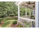 Inviting front porch with white railings and ceiling fans, overlooking a well-maintained lawn and mature trees at 1052 Avenue Of Oaks, Charleston, SC 29407