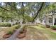 Charming home with a stone pathway leading to a cozy porch, a landscaped yard, and a mature tree at 1052 Avenue Of Oaks, Charleston, SC 29407