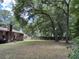 Large backyard featuring mature trees and partial view of a red brick house at 1056 Yorktown Dr, Charleston, SC 29412