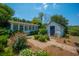 Lush backyard garden with a cottage and storage shed, featuring vibrant red flowers and peaceful landscaping at 1133 Highway 311, Cross, SC 29436