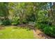 Beautiful backyard with mature trees, a bench, and lush green lawn creating a peaceful setting at 1133 Highway 311, Cross, SC 29436