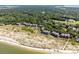 Expansive aerial view of coastal condos near sandy beach, lush greenery, and wooded landscape at 1334 Pelican Watch Villas, Seabrook Island, SC 29455