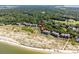 Expansive aerial view of coastal condos near sandy beach, lush greenery, and wooded landscape at 1334 Pelican Watch Villas, Seabrook Island, SC 29455