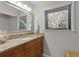 Bathroom features a large mirror, granite countertops, wooden cabinets, and a bright window at 146 High Hammock Villas, Seabrook Island, SC 29455