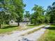 Charming home featuring a screened porch and a long gravel driveway, surrounded by lush greenery at 153 Willow Brook Way, Cordesville, SC 29434