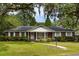Charming brick home featuring a well-manicured lawn, crisp white shutters and surrounded by mature trees at 1789 Balfoure Dr, Charleston, SC 29407