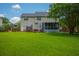 Lush backyard featuring a well maintained lawn, deck, and mature trees with a view of the home's exterior at 2005 Thornhill Dr, Summerville, SC 29485