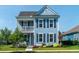 Charming two-story home with light blue siding, black shutters, and a quaint second-story porch at 2017 Geranium Ln, Johns Island, SC 29455