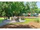 Community playground with a fire pit, featuring a variety of equipment for children in a lush, green space at 2017 Geranium Ln, Johns Island, SC 29455
