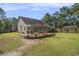 Wide backyard with a wooden deck, partially covered patio, and a fenced perimeter at 214 Deer Ridge Court Ct, Huger, SC 29450