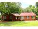 Charming brick home featuring a red metal roof, well-manicured lawn, and mature trees at 2206 Hunter Creek Dr, Charleston, SC 29414