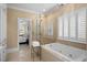 Bright bathroom with a glass-enclosed shower, soaking tub, and plantation shutters at 2340 Marsh Hen Dr, Seabrook Island, SC 29455