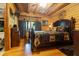 Cozy bedroom featuring log walls, wood floors, a ceiling fan, and a plush bed with decorative pillows at 24678 Augusta Hwy, Cottageville, SC 29435