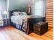 Cozy bedroom featuring a beautifully decorated bed, wood floors, wood walls and a vintage trunk at the foot of the bed at 24678 Augusta Hwy, Cottageville, SC 29435