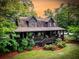 Aerial view of a charming log cabin with inviting porch and landscaped grounds at 24678 Augusta Hwy, Cottageville, SC 29435