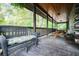 Spacious log cabin porch with wicker seating, picnic table, and wooded views at 24678 Augusta Hwy, Cottageville, SC 29435