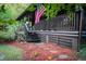 Rustic log cabin front porch with a cozy entrance, American flag, and mulch landscaping at 24678 Augusta Hwy, Cottageville, SC 29435