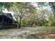 Expansive yard with mature trees, side porch, and classic log cabin design at 24678 Augusta Hwy, Cottageville, SC 29435