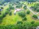 Aerial view of a home with a red roof, green lawns, trees, and a pool, in a rural setting at 274 Harvest Rd, Moncks Corner, SC 29461
