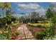 Brick path leads to a wooden back deck with seating, a teal umbrella and surrounding landscaping at 274 Harvest Rd, Moncks Corner, SC 29461