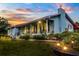 Charming home with a red roof is showcased at dusk, highlighting its inviting front porch and landscape lighting at 274 Harvest Rd, Moncks Corner, SC 29461