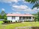 Inviting single-story home with a front yard, red metal roof, and landscaped garden at 274 Harvest Rd, Moncks Corner, SC 29461