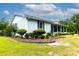 Side view of a beautiful single story home with landscaped garden, covered front porch, and red metal roof at 274 Harvest Rd, Moncks Corner, SC 29461