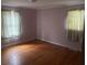 Bedroom featuring hardwood floors, two windows with green floral curtains, and light pink walls at 379 Chestnut Rd, Walterboro, SC 29488