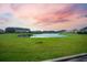 Scenic backyard view featuring a pond, expansive lawn, and vibrant sunset at 438 Flat Rock Ln, Summerville, SC 29486