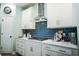 This kitchen features white cabinets, gold hardware, stainless steel vent hood, and blue backsplash at 4407 Palm Shadow Dr, Summerville, SC 29485