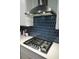 Close up of a modern gas range with a decorative tile backsplash and white cabinets at 4407 Palm Shadow Dr, Summerville, SC 29485