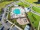 An aerial view of a community pool featuring seating, landscaping, playground, buildings, and parking at 4407 Palm Shadow Dr, Summerville, SC 29485