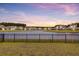 A serene backyard view showcases a scenic lake, a black metal fence, and the beauty of a colorful sunset at 515 Purple Finch Rd, Summerville, SC 29486