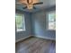 Light-filled bedroom featuring luxury vinyl plank flooring, ceiling fan, and two bright windows at 5513 Blackwell Ave # A, North Charleston, SC 29406