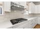 Close-up of the kitchen's range top, backsplash, quartz counters, stainless steel hood, and white shaker-style cabinets at 113 Jackson Pond Ct, Summerville, SC 29486