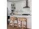 A close up of a kitchen island with white countertops and rattan stools at 1244 Crooked Oak Rd, Charleston, SC 29492