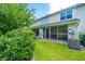 View of the home's back exterior and screened-in porch, surrounded by a well-maintained lawn at 125 Macy Cir, Goose Creek, SC 29445