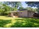 A brick house features a wooden deck, trees and a spacious grassy backyard fenced at the back at 1261 Hampshire Rd, Charleston, SC 29412