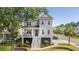 Charming gray two-story home boasts inviting front porch, manicured lawn, and lush landscaping on a sunny day at 1536 Keshi Pearl Dr, Mount Pleasant, SC 29466